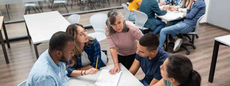 An image of educators working together around a table, in collaboration.