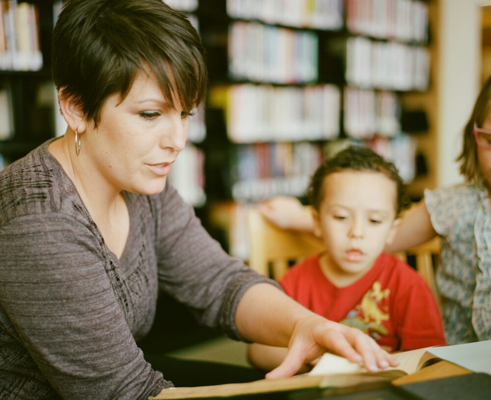 An adult educator helps a young child at school.