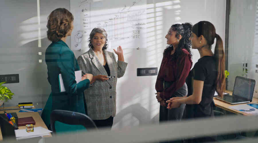 Woman speaks to group while presenting statistics on whiteboard