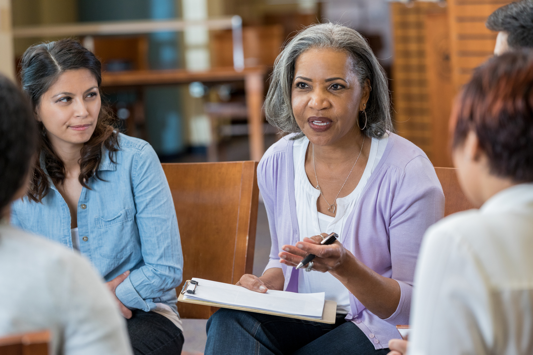 An African-American woman in conversation with peers in a circle.