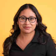 A headshot of Diana Ramos against a bright yellow backdrop